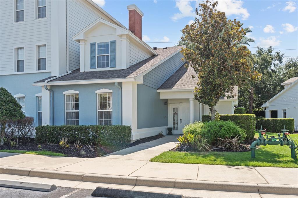 A blue-sided building with a white-trimmed entrance, a brick chimney, and a sidewalk — 7636 HERITAGE CROSSING WAY, REUNION, FL