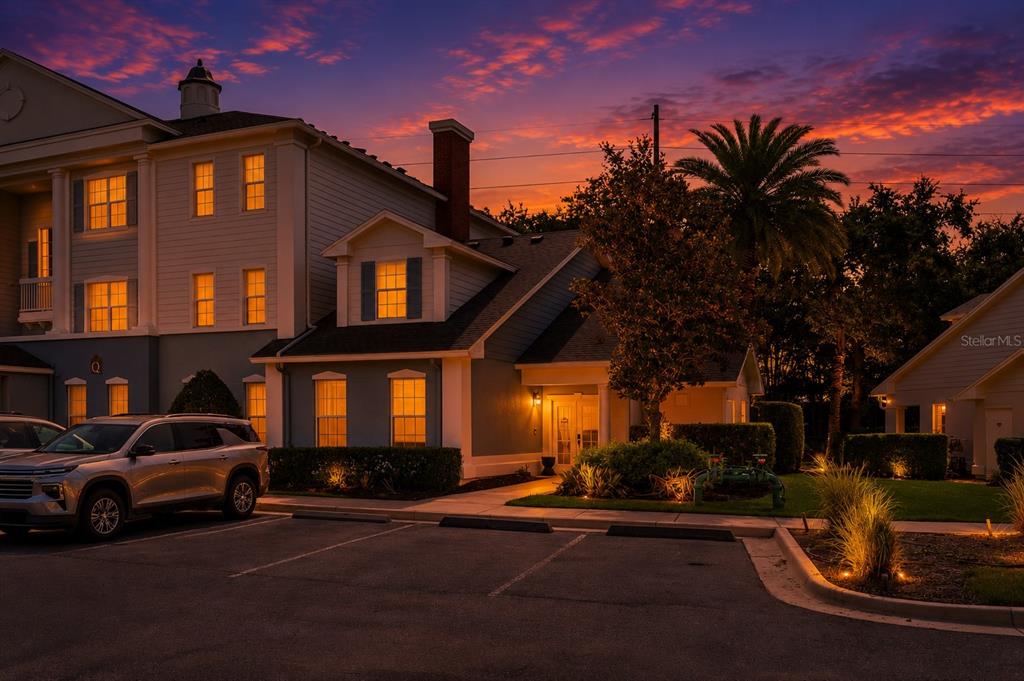 A multi-story building exterior at sunset with a parking lot and a silver SUV — 7636 HERITAGE CROSSING WAY, REUNION, FL