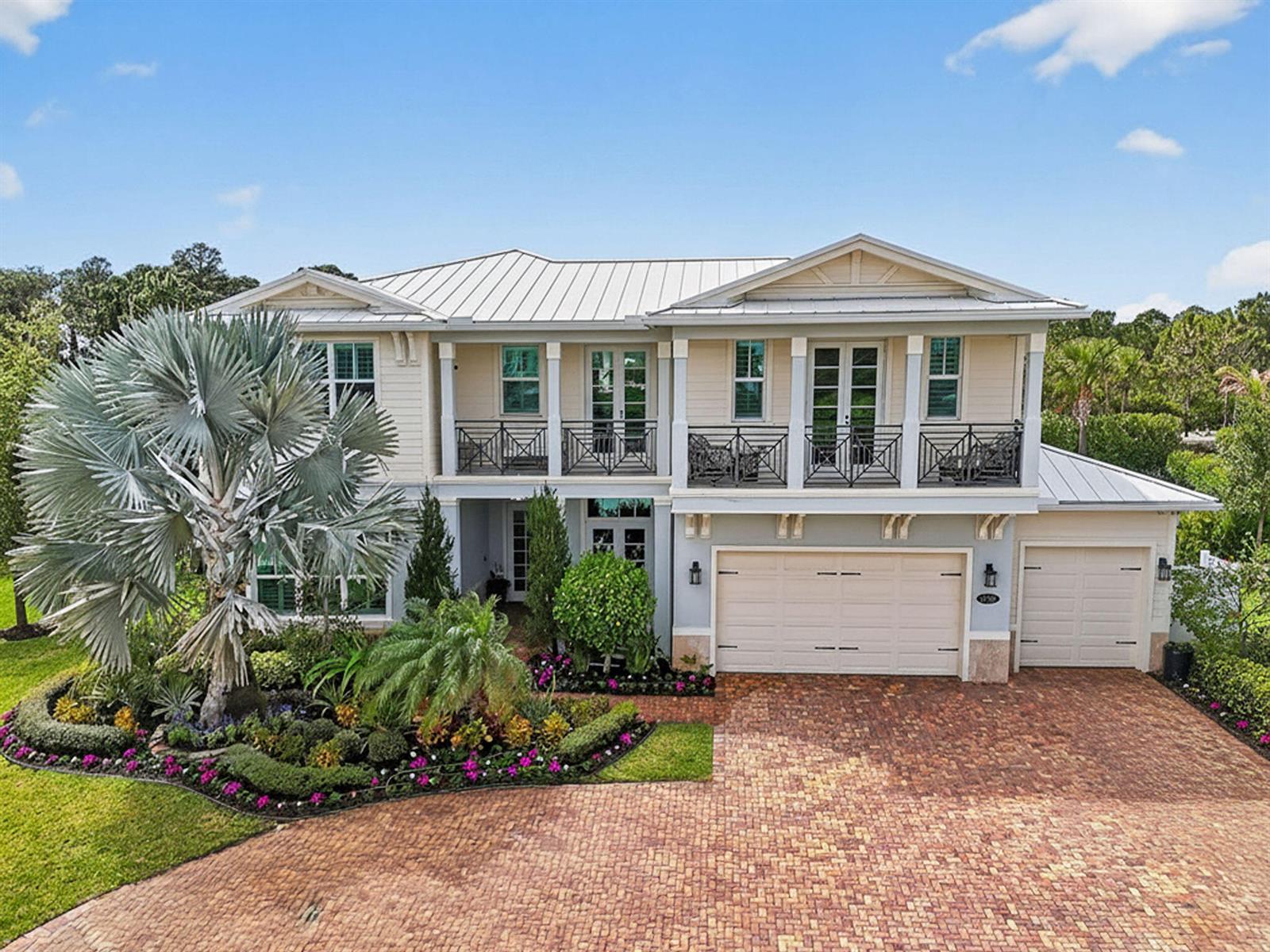 A two-story house with a metal roof, a brick driveway, and a second-floor balcony — 19966 SE Gallberry Drive, Jupiter FL 33458, JUPITER, FL