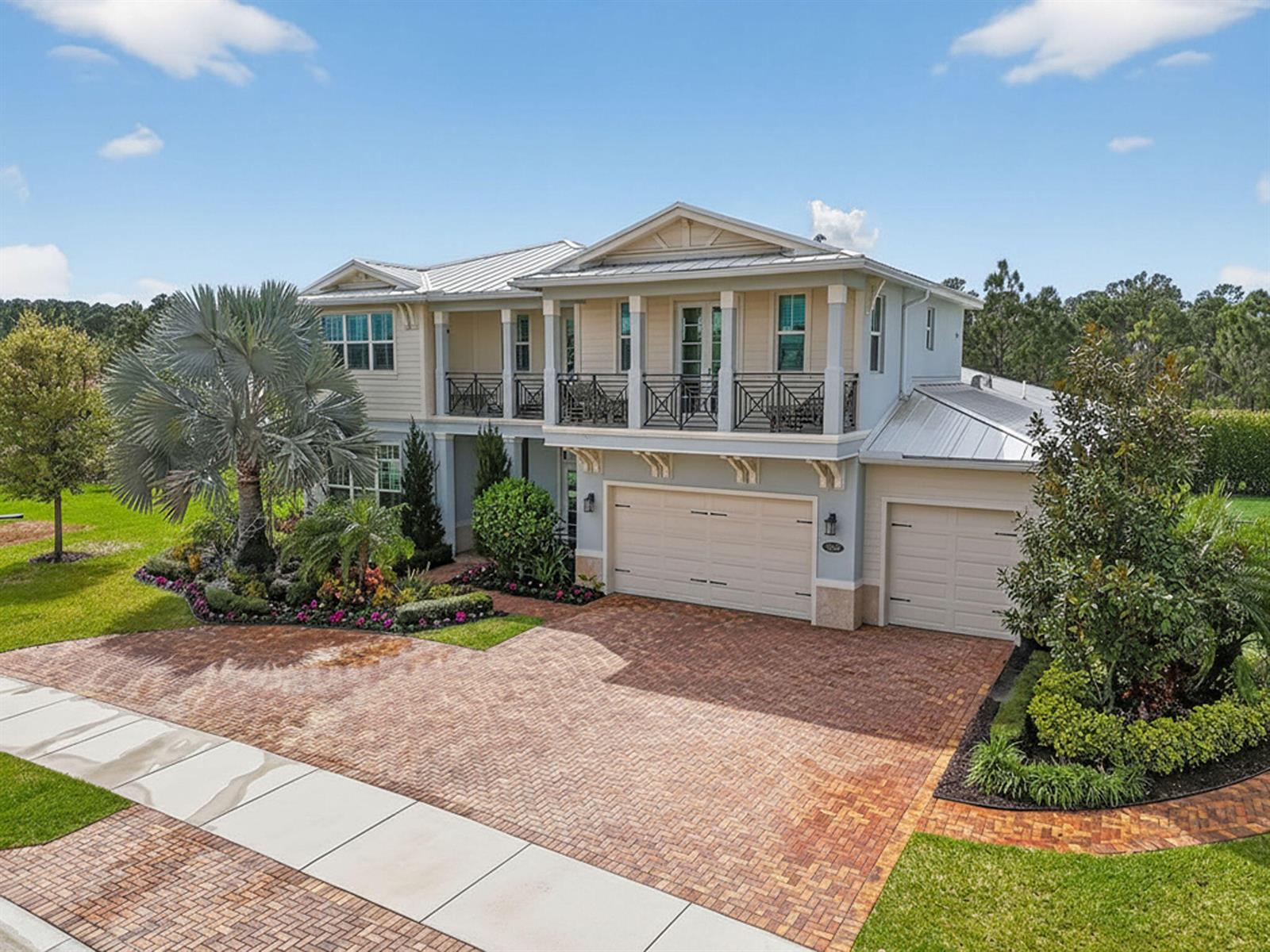 A two-story house with a brick driveway, metal roof, and a second-floor balcony — 19966 SE Gallberry Drive, Jupiter FL 33458, JUPITER, FL