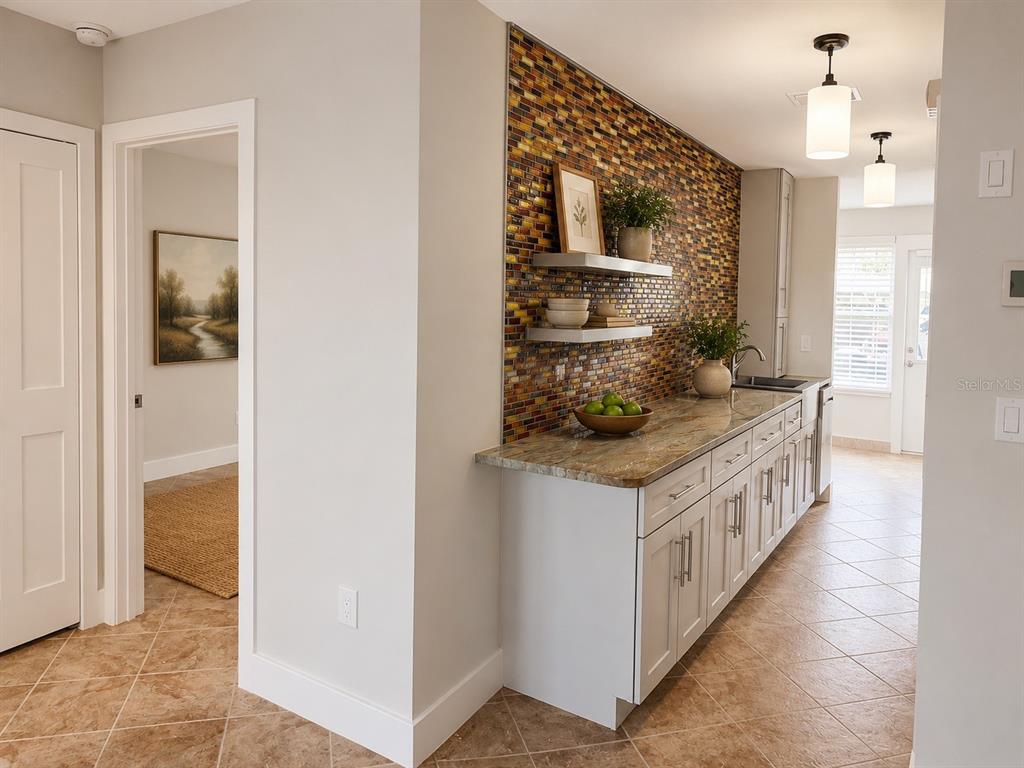 A kitchen area features white cabinets, granite countertops, and a decorative mosaic tile backsplash — 3128 59TH STREET S UNIT 109, GULFPORT, FL