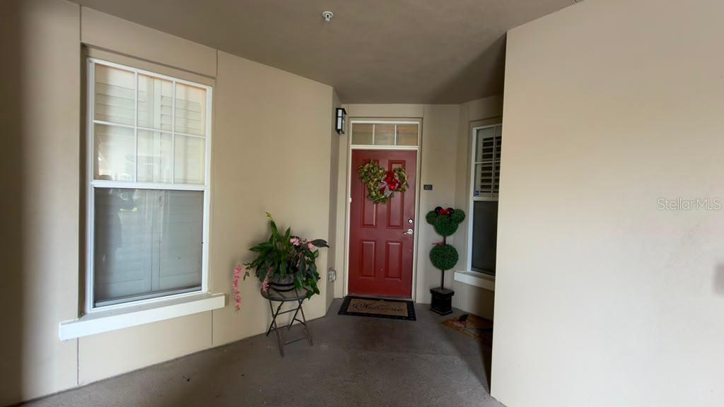 A covered entryway features a red front door, a potted plant, and a topiary — 1400 CELEBRATION AVENUE UNIT 105, CELEBRATION, FL