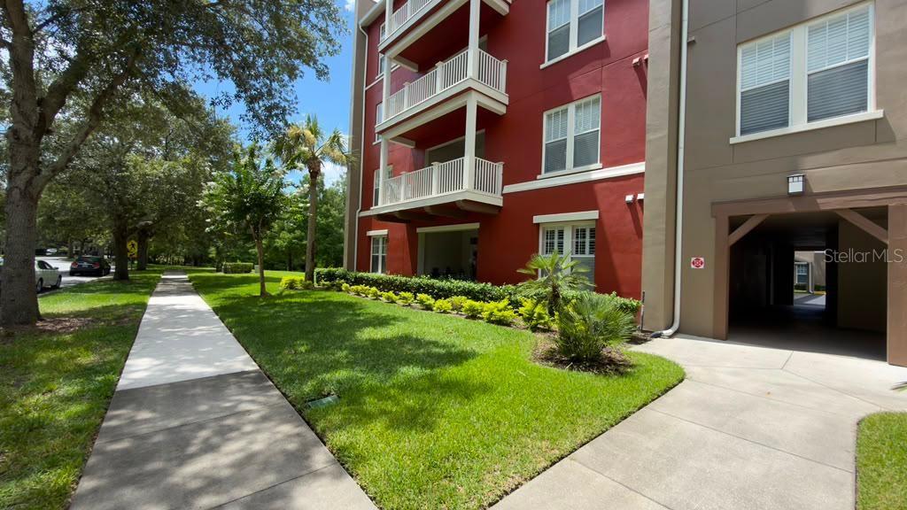 A multi-story red apartment building features white balconies and a ground-level covered entryway — 1400 CELEBRATION AVENUE UNIT 105, CELEBRATION, FL