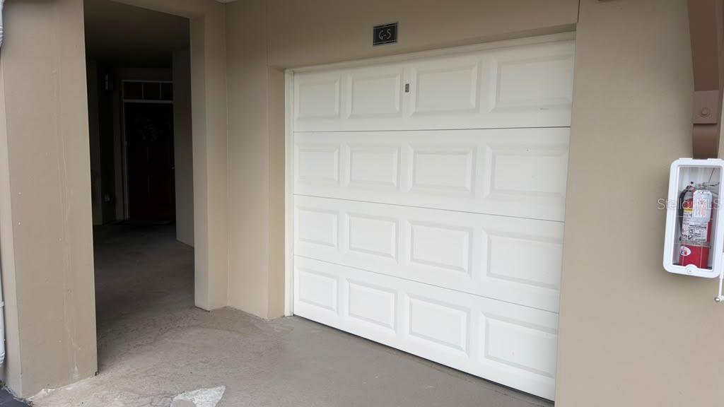 A white garage door is positioned next to an open entryway with a fire extinguisher nearby — 1400 CELEBRATION AVENUE UNIT 105, CELEBRATION, FL