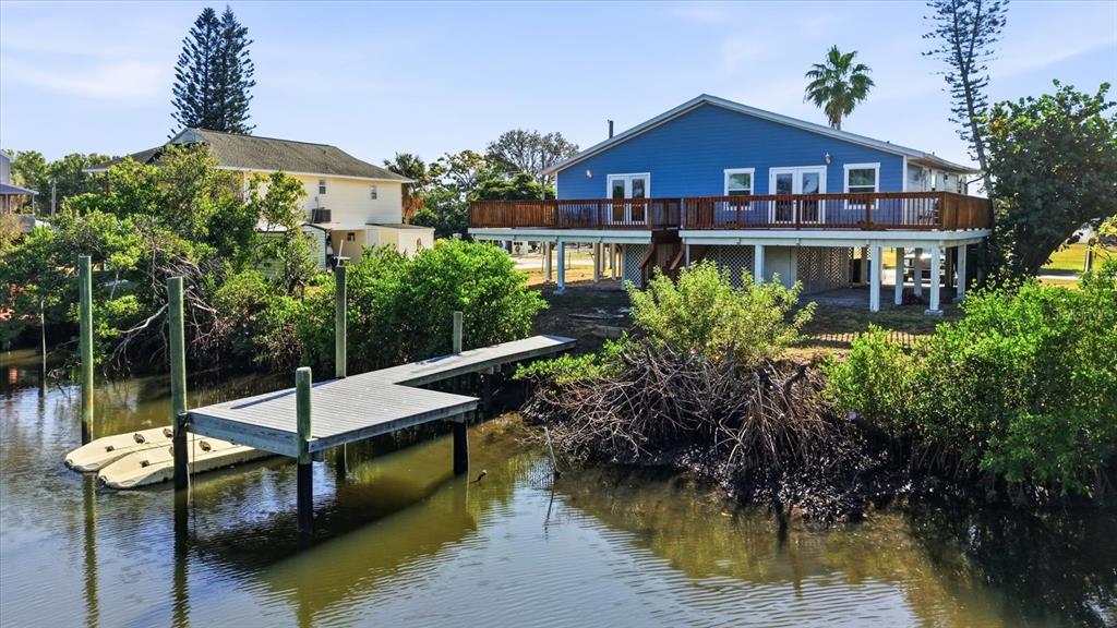 A blue elevated house sits next to a wooden dock on a canal — 3303 W SHELL POINT #A ROAD, RUSKIN, FL
