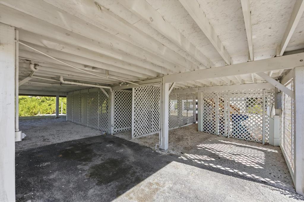 A covered ground-level parking area features a concrete floor, white lattice walls, and exposed beams — 3303 W SHELL POINT #A ROAD, RUSKIN, FL