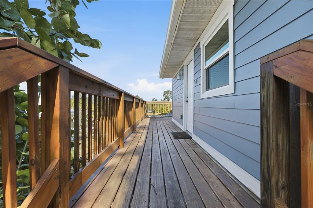 A wooden deck with a railing runs alongside the blue-sided exterior of a house — 3303 W SHELL POINT #A ROAD, RUSKIN, FL