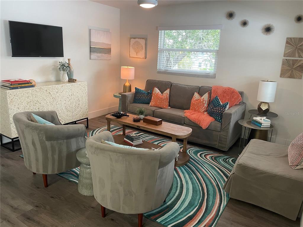 A living room features a gray sofa, two armchairs, a patterned rug, and a television — 1910 MORRILL STREET UNIT 6, SARASOTA, FL