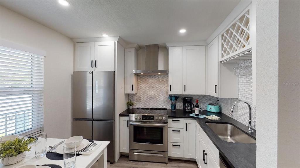 A kitchen features white cabinets, stainless steel appliances, a dark countertop, and a tiled backsplash — 1910 MORRILL STREET UNIT 6, SARASOTA, FL