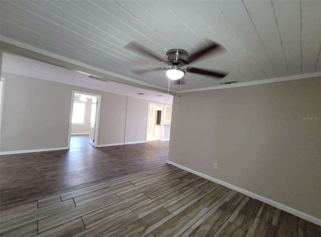 A room with wood-look tile flooring, a white plank ceiling, and a ceiling fan — 1504 E 99TH AVENUE UNIT A, TAMPA, FL