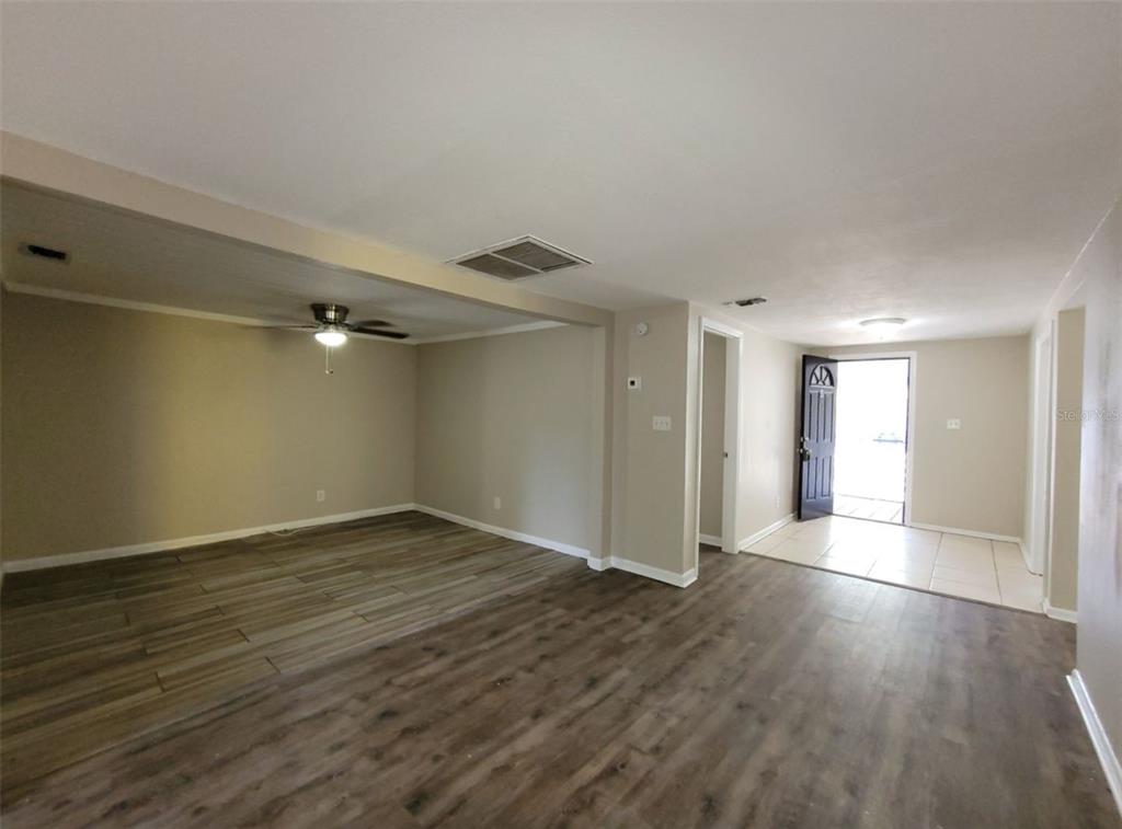 An open-concept living area features wood-look flooring, a ceiling fan, and a tiled entryway — 1504 E 99TH AVENUE UNIT A, TAMPA, FL