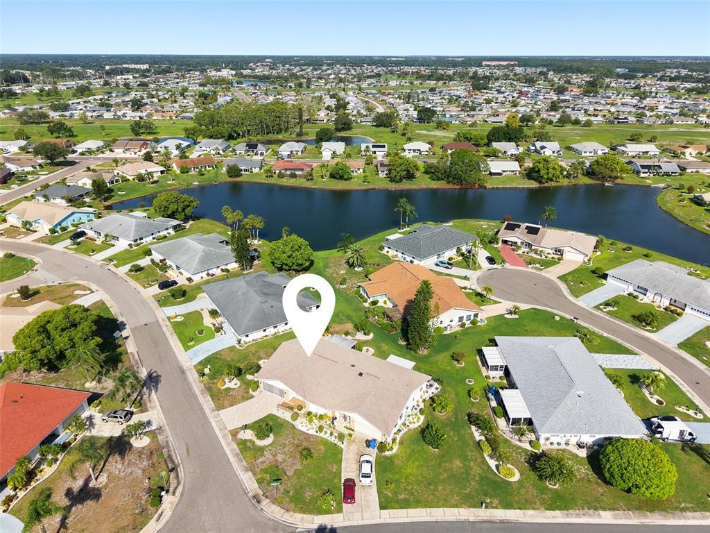 An aerial view shows a residential house with a white location pin on its roof — 127 WINTERSONG LANE, SUN CITY CENTER, FL