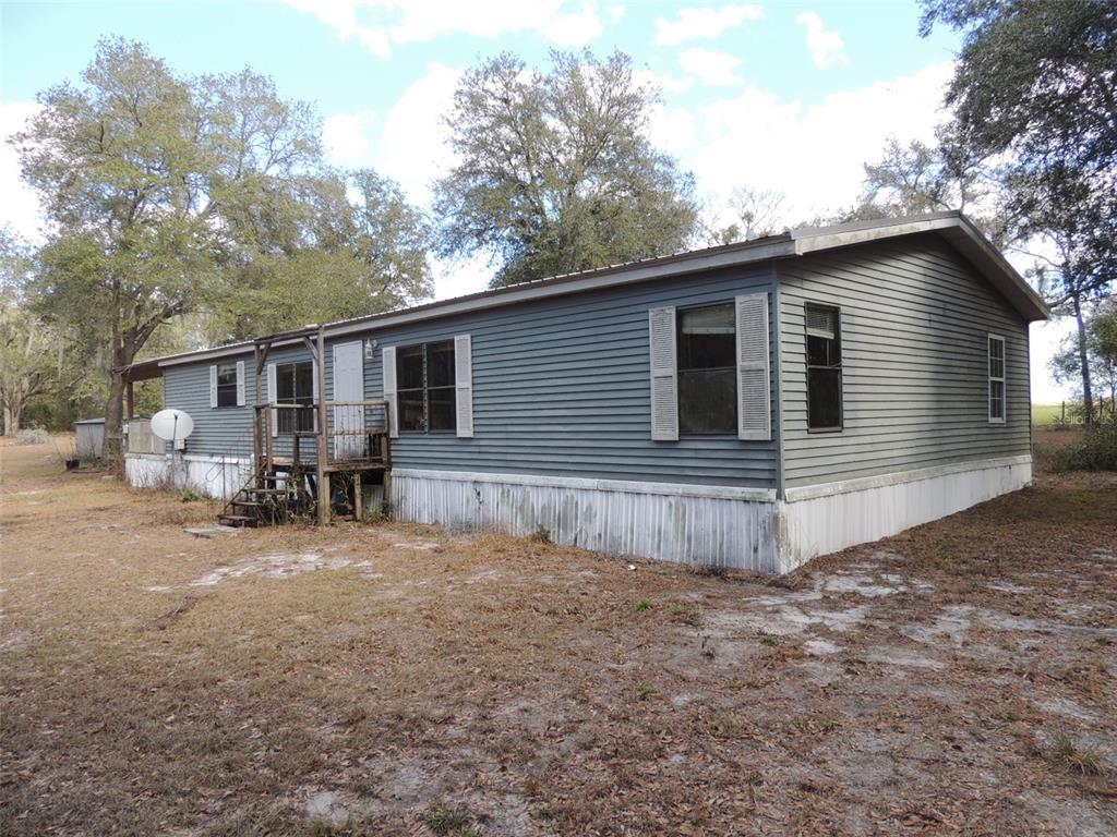 A single-story manufactured home with gray siding and a wooden porch sits on a lot — 4551 SE 138TH TERRACE, MORRISTON, FL