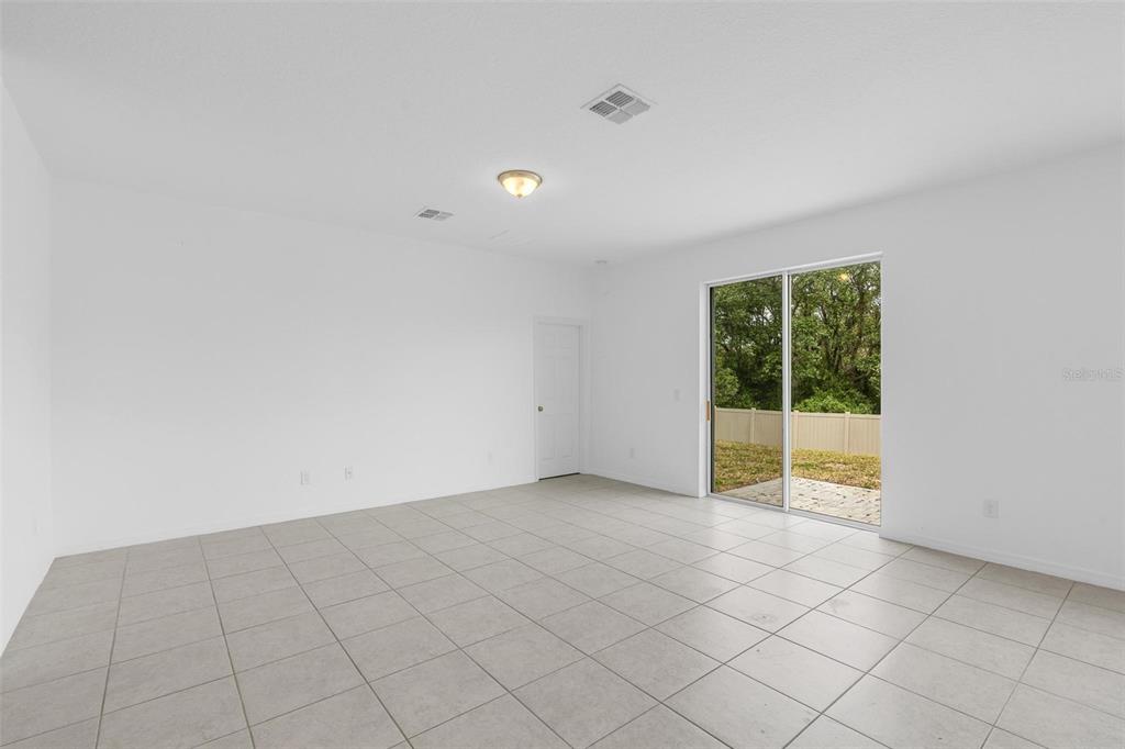 A bright, empty room with white walls, tile flooring, and a sliding glass door — 663 FAIRVIEW AVENUE, HAINES CITY, FL