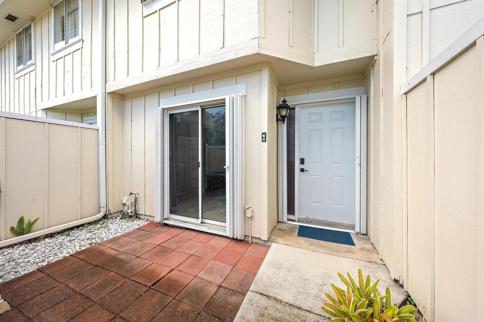 A patio with red pavers sits in front of a sliding glass door and entrance — 6158 Riverwalk Lane # 6, Jupiter FL 33458, JUPITER, FL