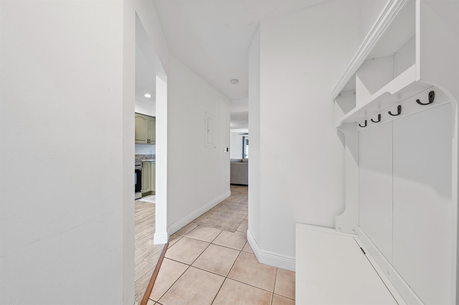 A tiled hallway features a white coat rack and leads to a kitchen and living area — 6158 Riverwalk Lane # 6, Jupiter FL 33458, JUPITER, FL