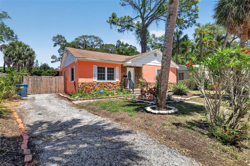A single-story house with orange stucco walls, a stone base, and a gravel driveway — 775 28TH AVENUE S, ST PETERSBURG, FL