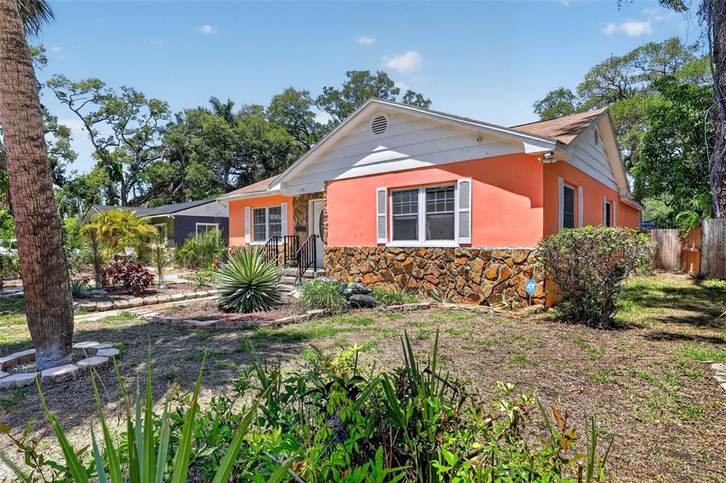 A single-story house with orange stucco walls, a stone base, and a white gabled roof — 775 28TH AVENUE S, ST PETERSBURG, FL