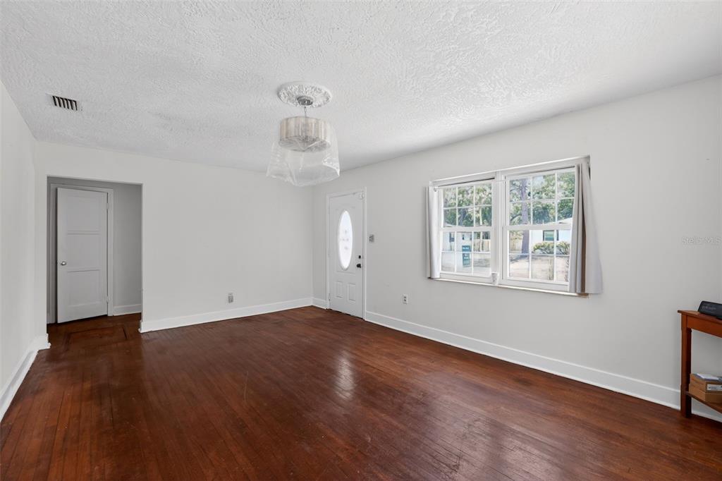 An empty room with white walls, dark wood flooring, a ceiling light, and a front door — 775 28TH AVENUE S, ST PETERSBURG, FL