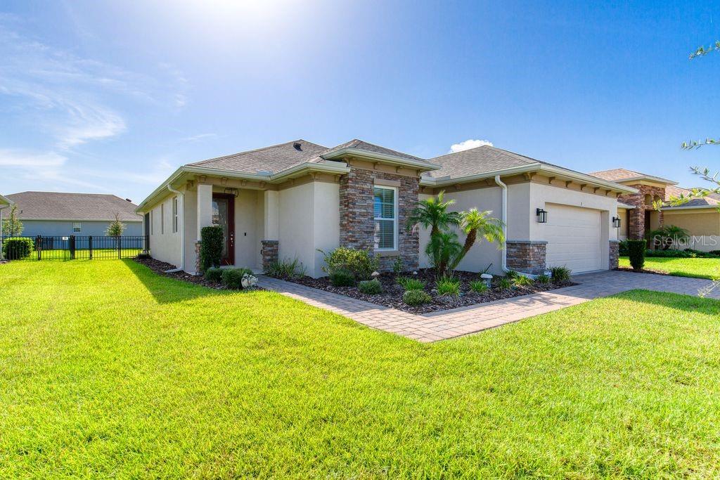 A single-story house with a beige stucco exterior, stone accents, and a two-car garage — 5 SHEAR WATER TRAIL, ORMOND BEACH, FL