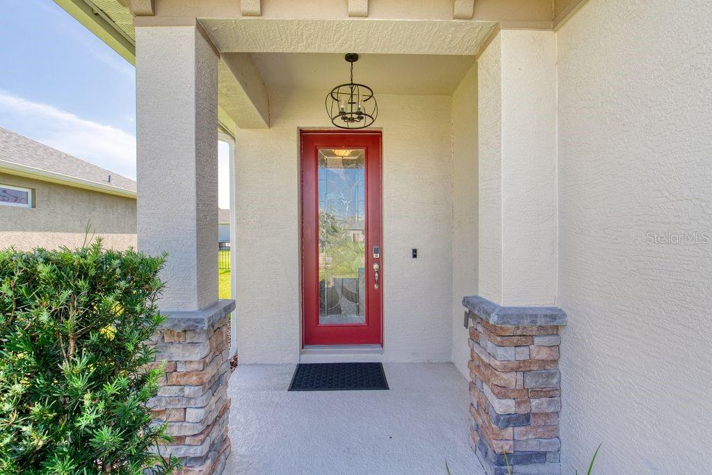 A covered front entryway features a red door with a glass insert and stone pillars — 5 SHEAR WATER TRAIL, ORMOND BEACH, FL