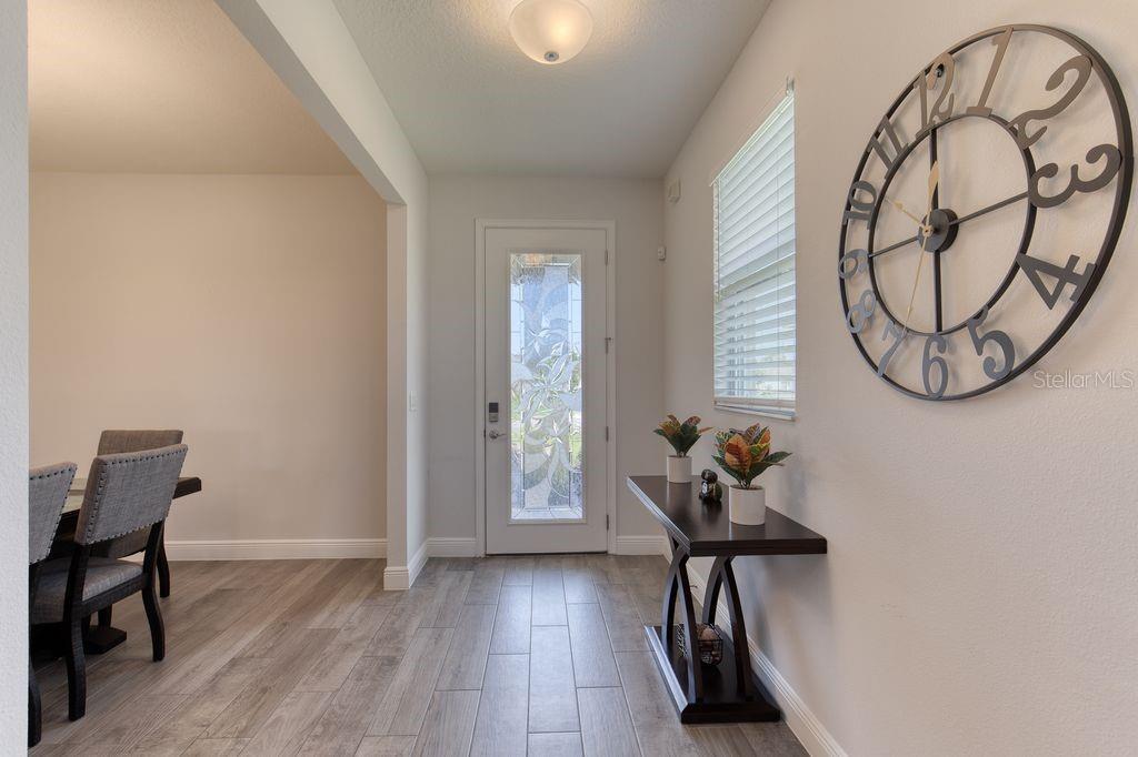 An entryway features wood-look tile flooring, a decorative wall clock, and a glass-paneled front door — 5 SHEAR WATER TRAIL, ORMOND BEACH, FL