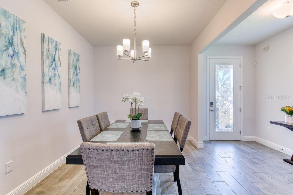 A dining room features a dark wood table, gray upholstered chairs, and a modern chandelier — 5 SHEAR WATER TRAIL, ORMOND BEACH, FL