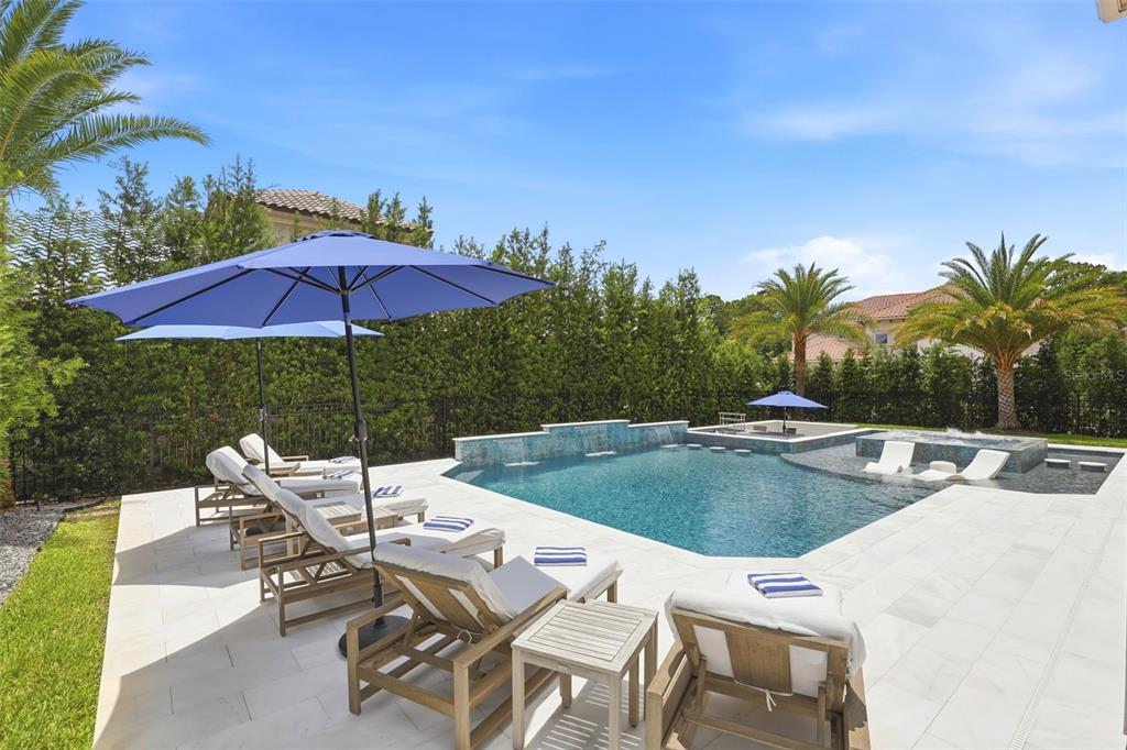 A backyard swimming pool with lounge chairs, umbrellas, and a spa under a blue sky — 3851 GRASSLAND LOOP, LAKE MARY, FL
