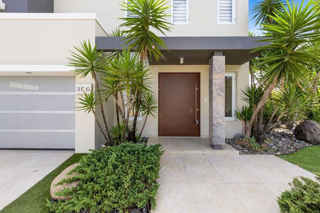 The exterior of a modern house features a wooden front door and a garage — 366 ALMACIGO, SAN JUAN, PR