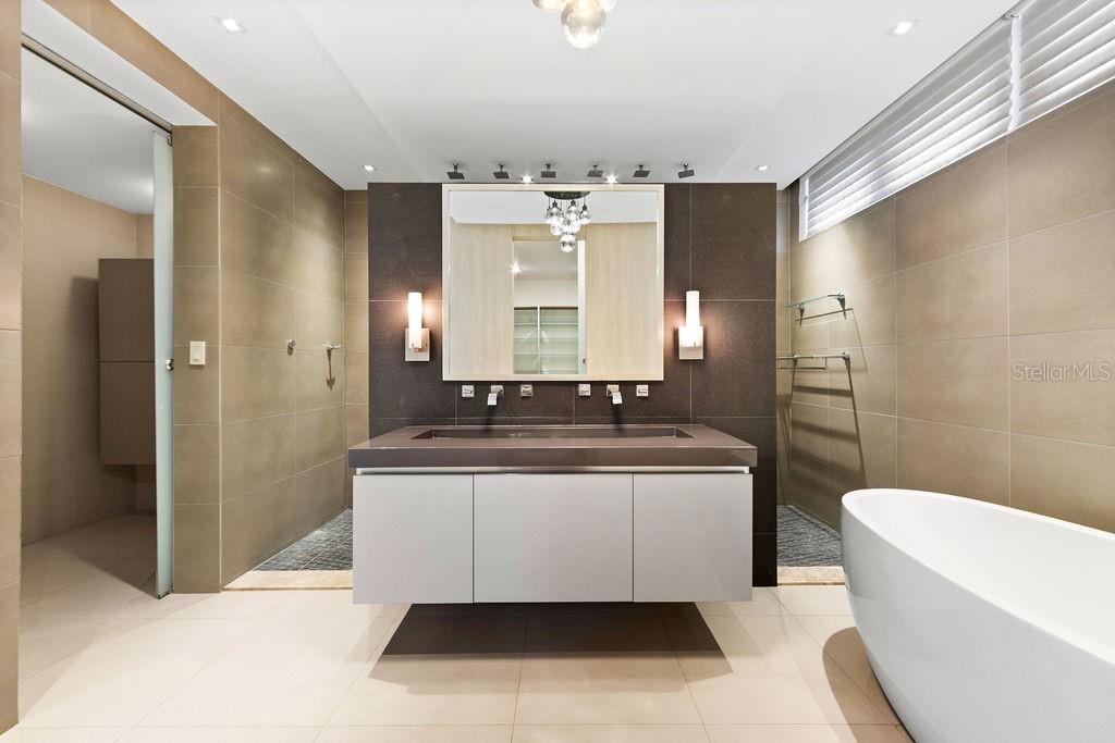 A modern bathroom features a floating double vanity, a freestanding tub, and large-format tile walls — 366 ALMACIGO, SAN JUAN, PR
