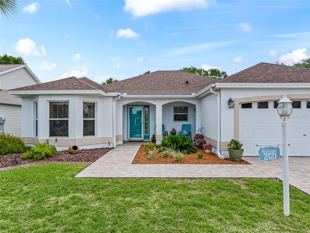 An aerial view of a single-story house with a paved driveway and a golf course backdrop — 2121 GERARDO AVENUE, THE VILLAGES, FL