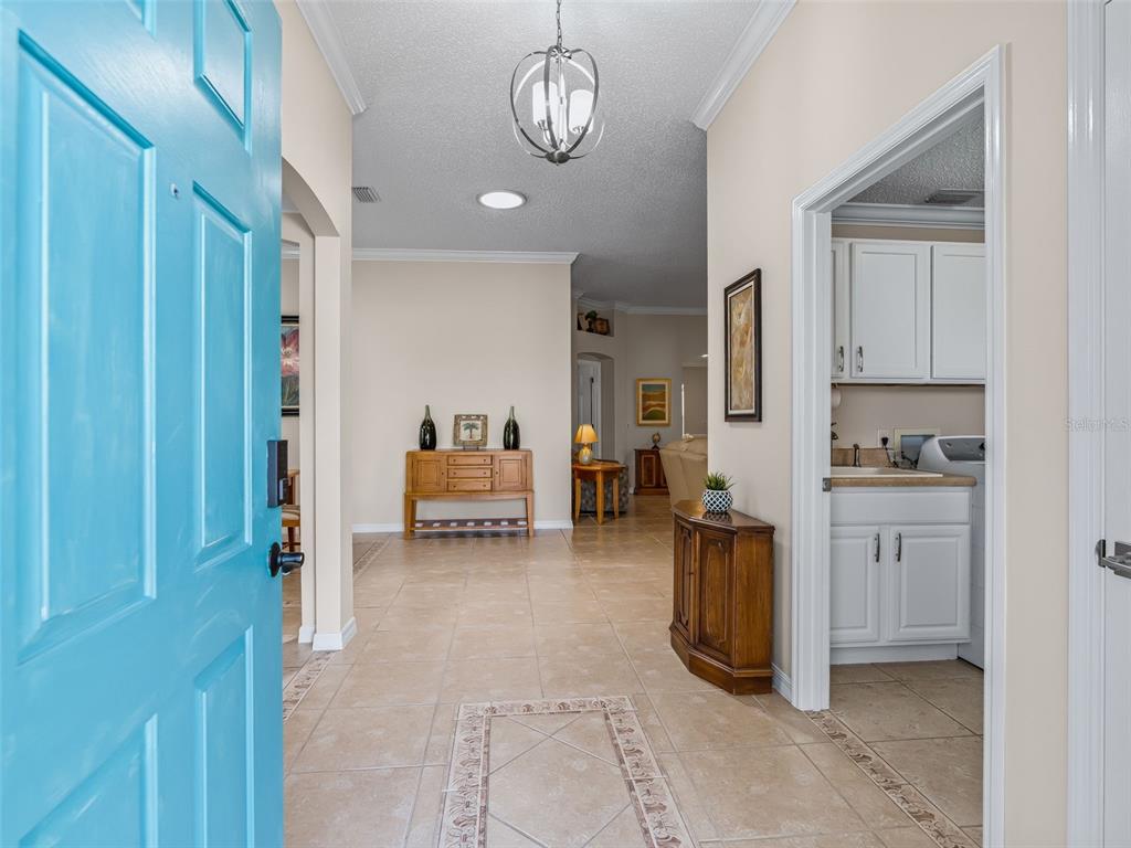 The exterior of a house features a teal front door, a covered porch, and landscaping — 2121 GERARDO AVENUE, THE VILLAGES, FL
