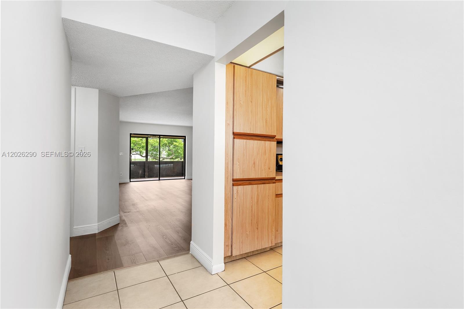 A tiled entryway leads to a living area with wood flooring and a sliding glass door — 4950 E Sabal Palm Blvd # 106, Tamarac FL 33319, TAMARAC, FL