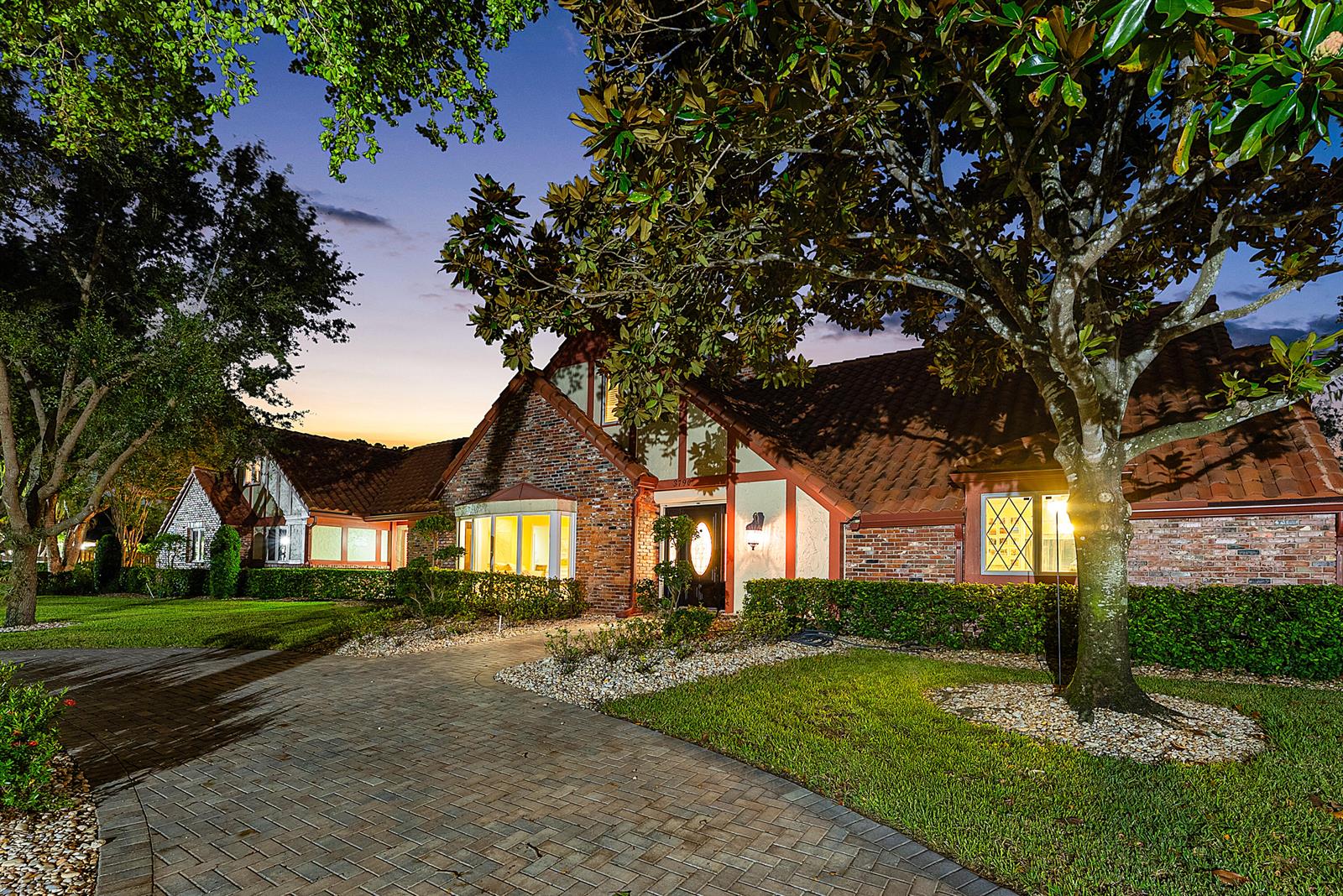 A brick and stucco house with a tiled roof at dusk features a paved driveway — 3790 Kings Way, Boca Raton FL 33434, BOCA RATON, FL
