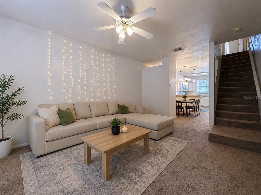 A living room features a beige sectional sofa, a wooden coffee table, and string lights — 3920 SW 20TH AVENUE UNIT 1306, GAINESVILLE, FL