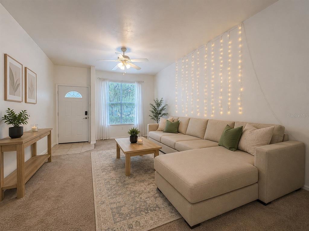 A living room features a beige sectional sofa, a wooden coffee table, and string lights — 3920 SW 20TH AVENUE UNIT 1306, GAINESVILLE, FL