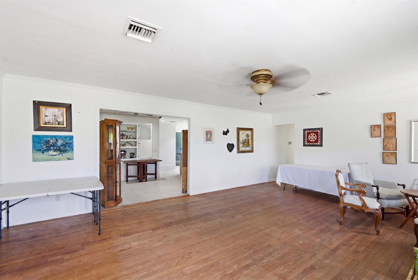 A spacious living room features white walls, hardwood floors, a ceiling fan, and folding tables — 303 Cornell Drive, FL 33460, FL