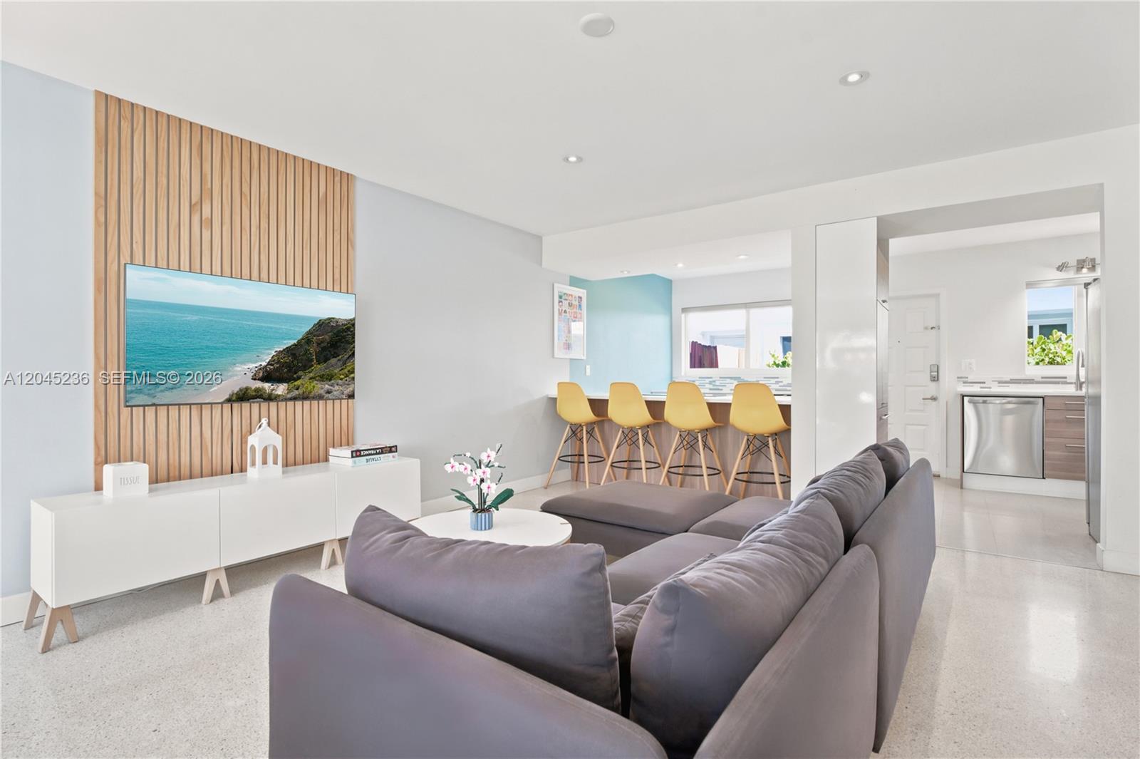 A living room features a grey sectional sofa, a wood-slatted accent wall, and bar seating — 7334 Gary Ave # 7334, Miami Beach FL 33141, MIAMI BEACH, FL