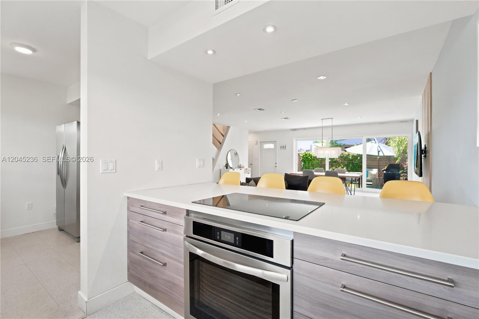 A kitchen island with a built-in cooktop and oven faces an open-concept living area — 7334 Gary Ave # 7334, Miami Beach FL 33141, MIAMI BEACH, FL