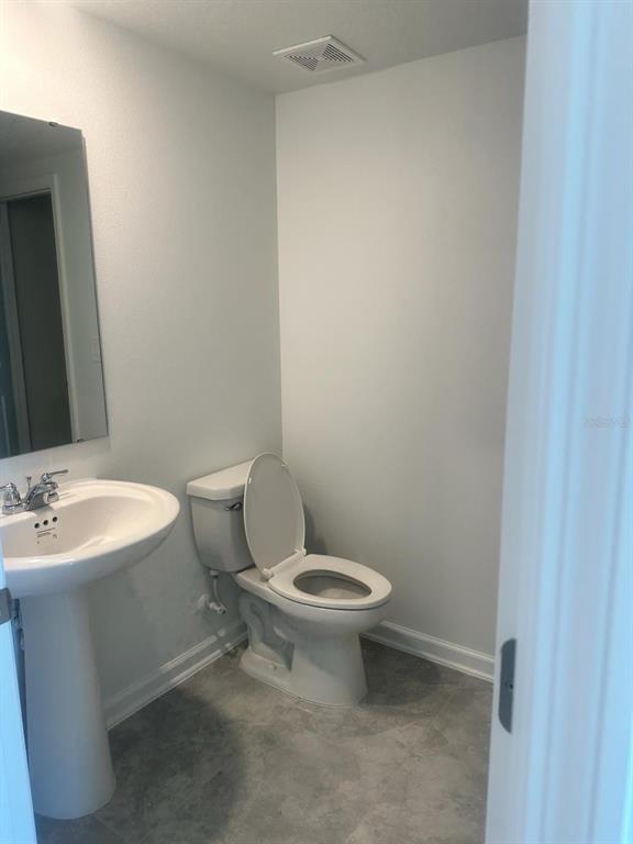 A small bathroom features a pedestal sink, a white toilet, and gray tile flooring — 3319 LAURENT LOOP UNIT 3319, DAVENPORT, FL