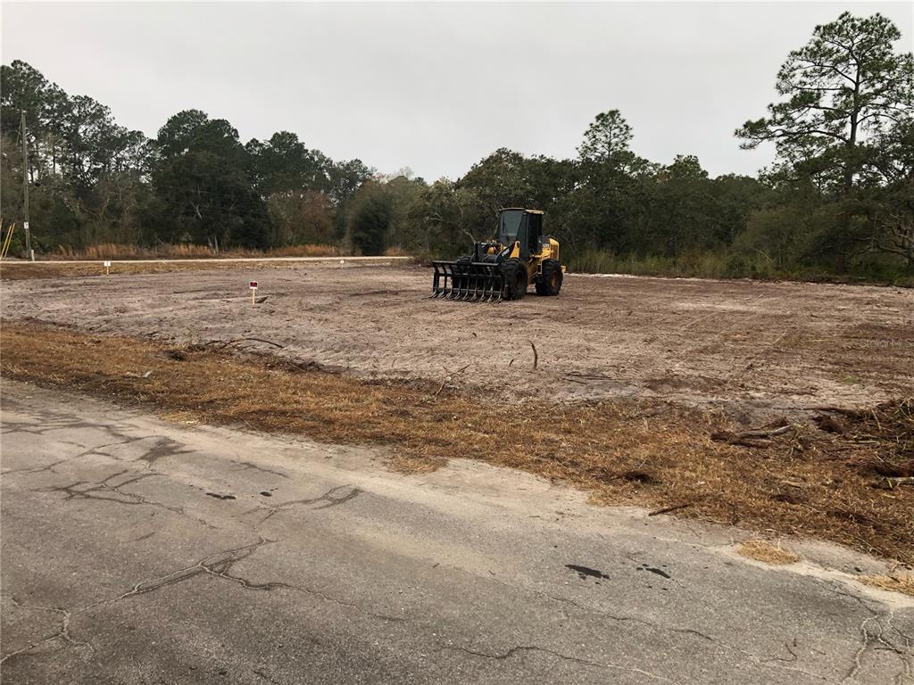 A yellow tractor sits on a cleared, sandy residential lot next to a paved road — 000 FISHER LOOP, OCKLAWAHA, FL
