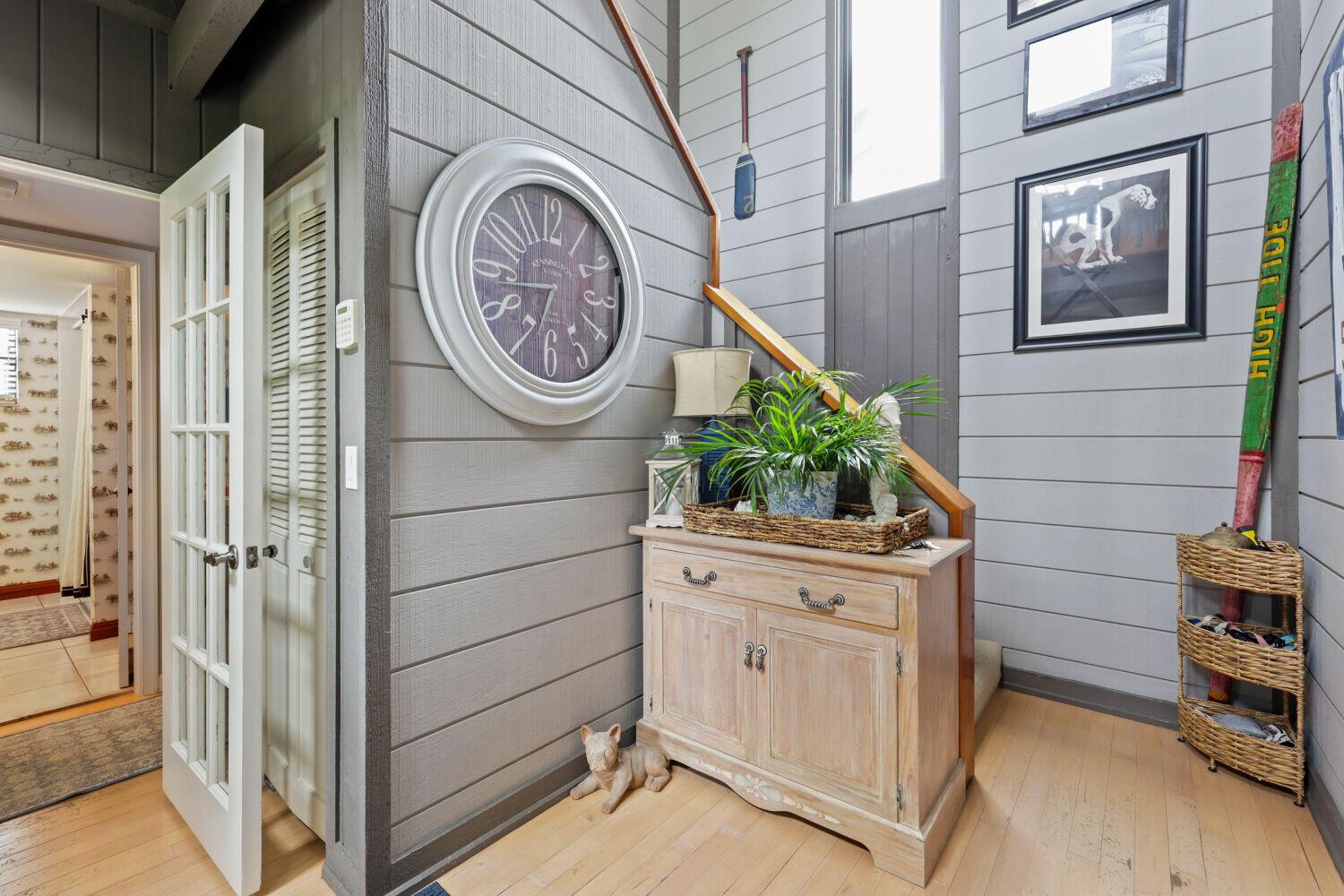 A hallway features a wooden cabinet, a large wall clock, and stairs with a wooden railing — 3918 Edgar Avenue, Boynton Beach FL 33436, BOYNTON BEACH, FL