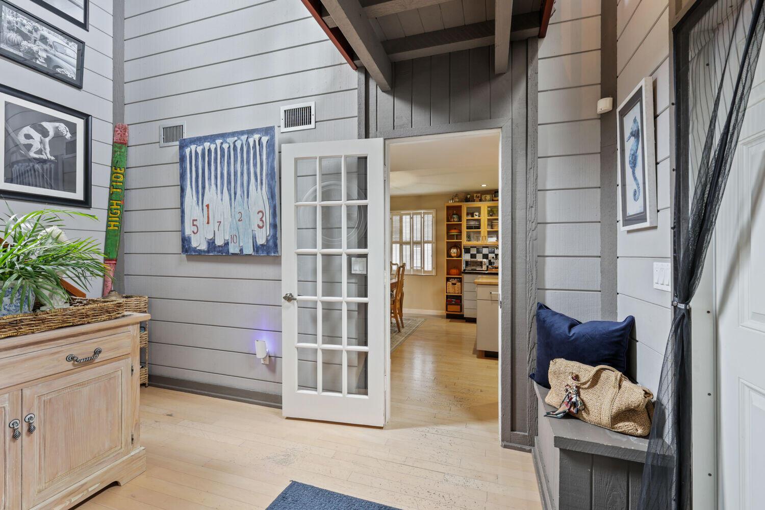 A hallway features light wood floors, gray shiplap walls, a white French door, and decor — 3918 Edgar Avenue, Boynton Beach FL 33436, BOYNTON BEACH, FL