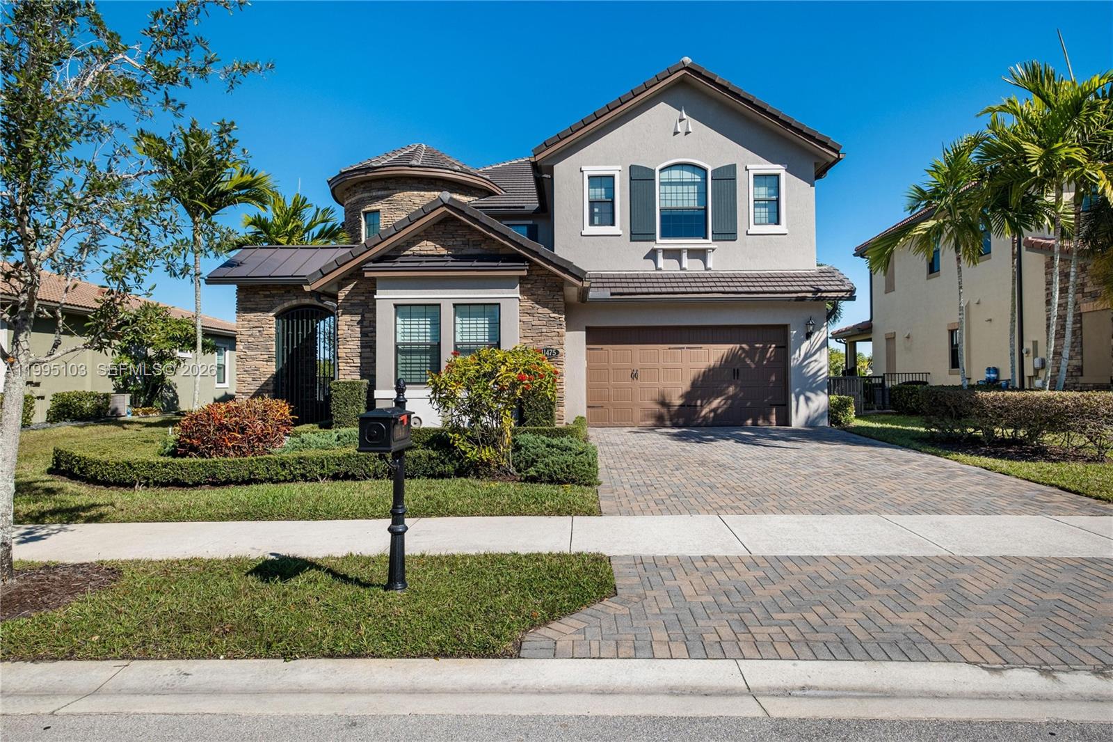 A two-story suburban house features a stone facade, a paved driveway, and a garage — 11475 Watercrest Circle East, Parkland FL 33076, PARKLAND, FL