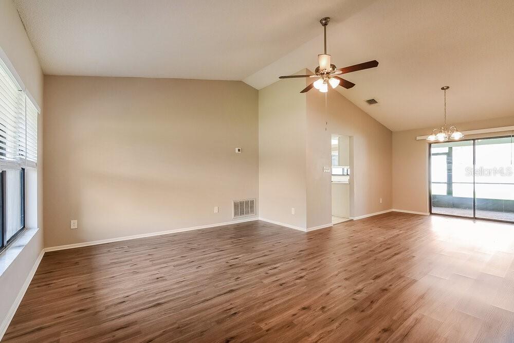 An empty living room with wood-look flooring, a vaulted ceiling, and a ceiling fan — 1014 DISHMAN LOOP, OVIEDO, FL