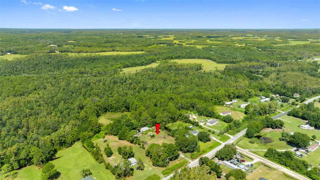 An aerial view shows a rural property with a red arrow pointing toward a cleared lot — 3207 CYPRESS TRAILS DRIVE, POLK CITY, FL
