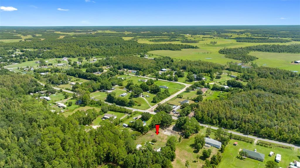 An aerial view shows a rural residential lot marked by a red arrow among trees — 3207 CYPRESS TRAILS DRIVE, POLK CITY, FL