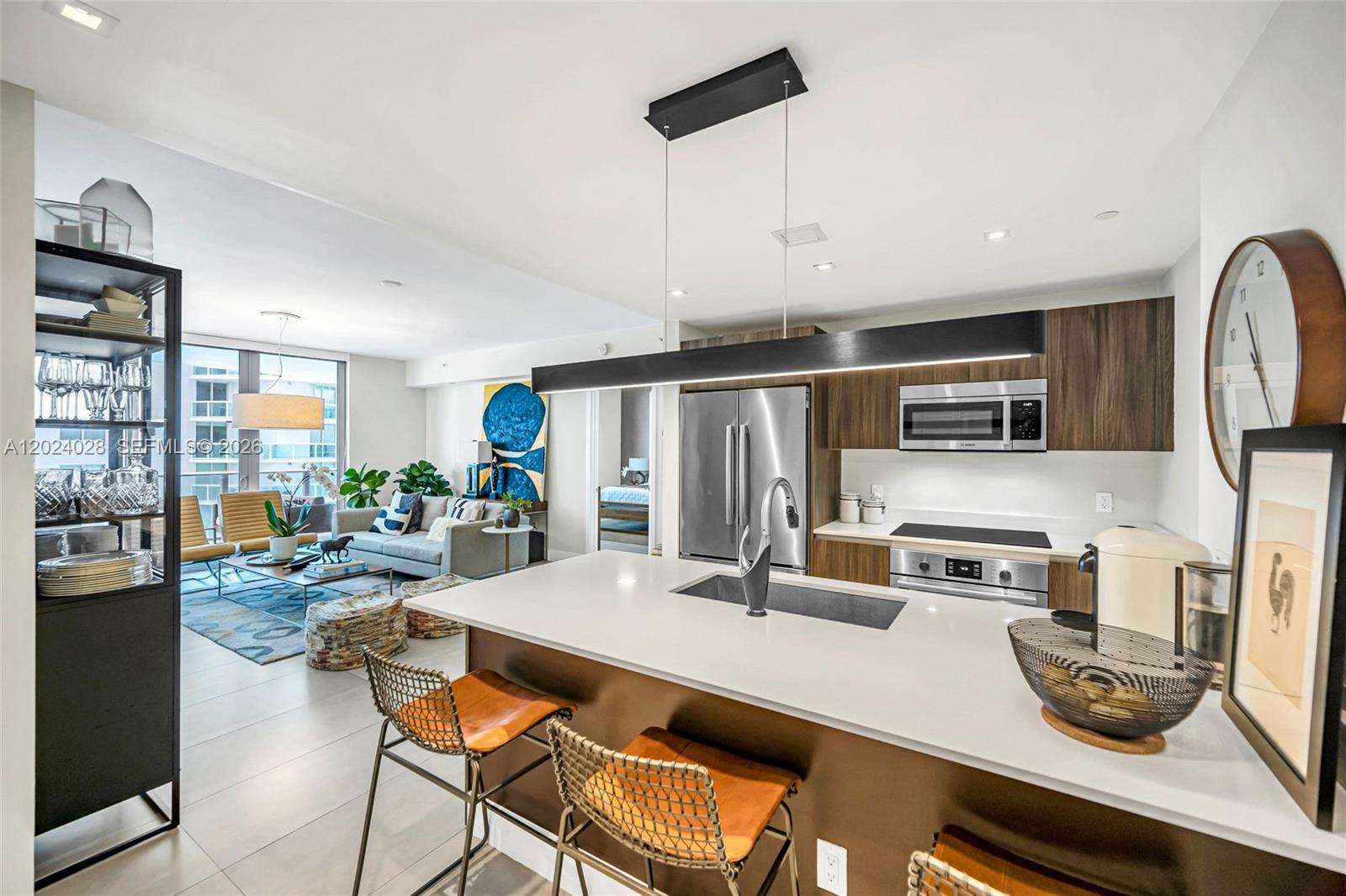 A modern open-concept kitchen and living area featuring a large island and wood cabinetry — 488 NE 18th St # 2011, Miami FL 33132, MIAMI, FL