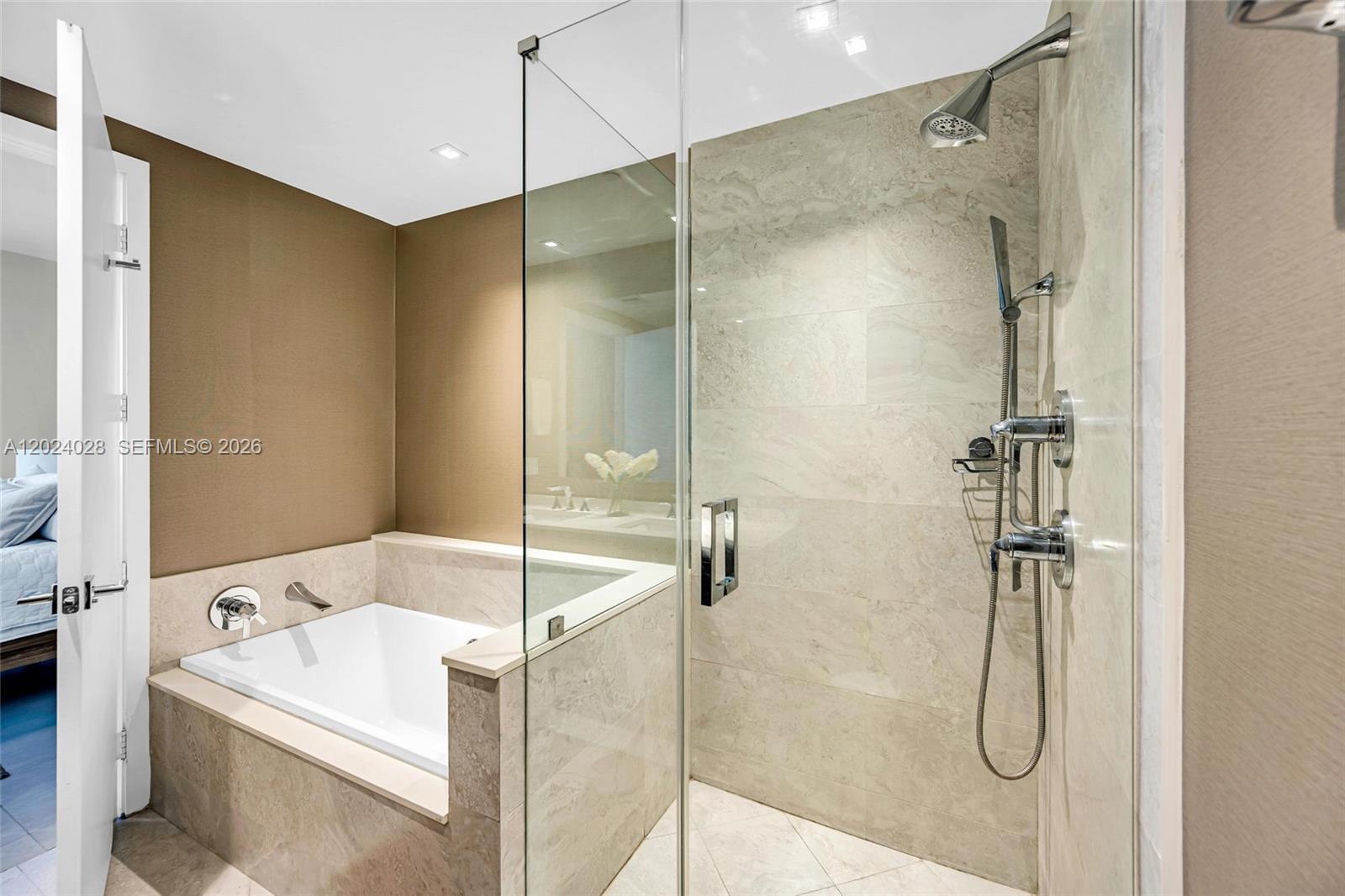 A bathroom features a white soaking tub and a glass-enclosed shower with stone tile — 488 NE 18th St # 2011, Miami FL 33132, MIAMI, FL