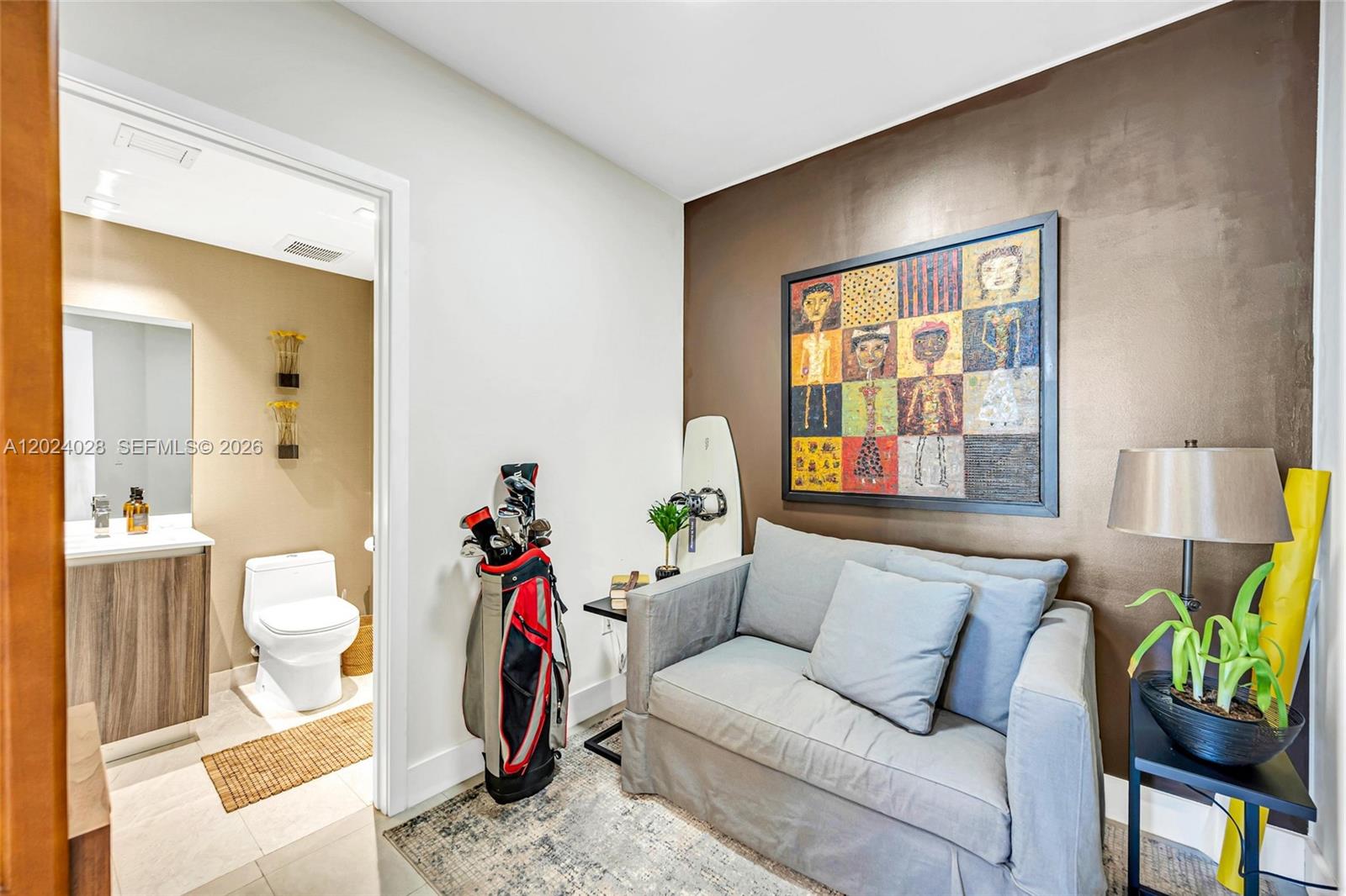 A small room features a grey sofa, a golf bag, and an adjacent bathroom — 488 NE 18th St # 2011, Miami FL 33132, MIAMI, FL